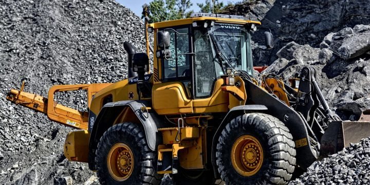 Orange and Black Tractor Next to Piles of Rocks